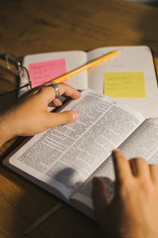 A person studying an open Bible with notes.